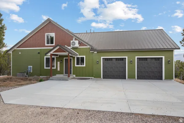 View of front of property with an attached garage, concrete driveway, and a metal roof