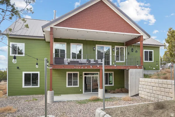 Rear view of property with board and batten siding, a metal roof, and a patio area