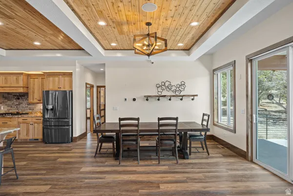 Dining space featuring dark wood-type flooring, a wood tray ceiling, and suspended lighting