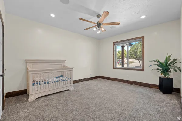 Unfurnished bedroom featuring carpet, a crib, ceiling fan, and recessed lighting