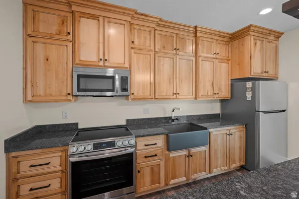 Kitchen with stainless steel appliances, dark stone countertops, recessed lighting, and light wood finish cabinetry