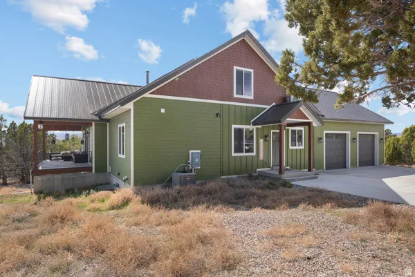 View of front of home featuring board and batten siding, an attached garage, driveway, and a metal roof