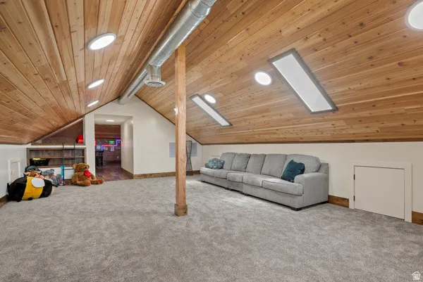 Additional living space with carpet flooring, a wooden ceiling with exposed beams, recessed lighting, and a skylight