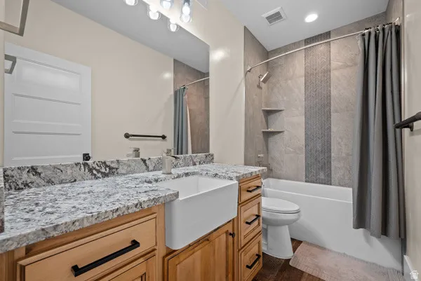 Bathroom with vanity, shower / tub combo with curtain, and dark wood-style floors
