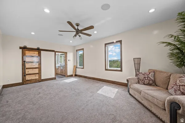 Living room featuring a barn door, healthy amount of natural light, recessed lighting, carpet, and a ceiling fan