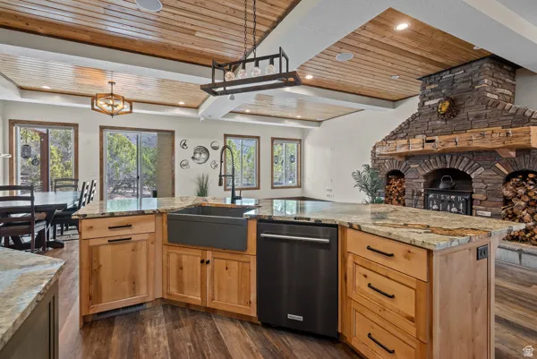 Kitchen with wood ceiling, light wood finish cabinets, light stone counters, open floor plan, and dark wood finished floors