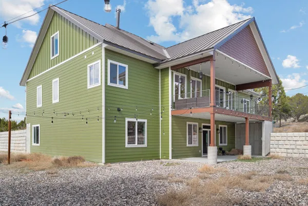 Rear view of property with board and batten siding, a patio area, a standing seam roof, and a balcony