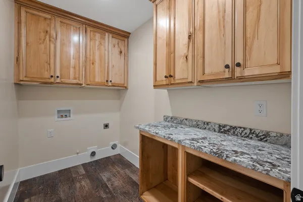 Laundry area with dark wood finished floors, washer hookup, electric dryer hookup, gas dryer hookup, and cabinet space