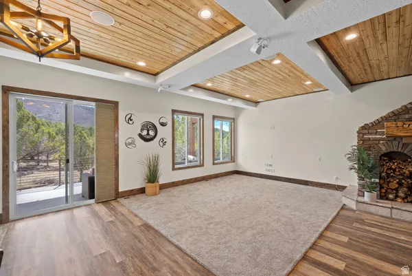 Unfurnished living room with wooden ceiling, a fireplace, wood finished floors, and a chandelier