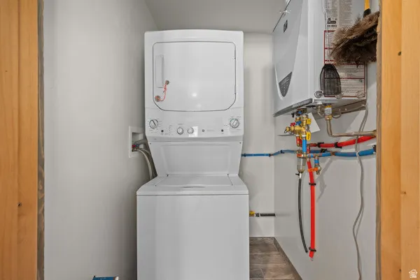 Laundry room featuring stacked washer and dryer and water heater