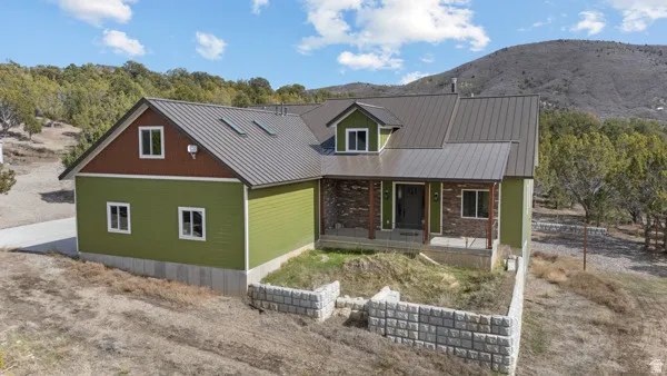 View of front of property with a porch, a mountain view, a standing seam roof, and dirt driveway