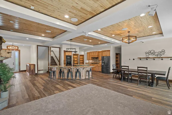Living room featuring a wood tray ceiling, suspended lighting, and dark wood-style floors