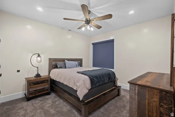 Bedroom featuring dark carpet, ceiling fan, and recessed lighting