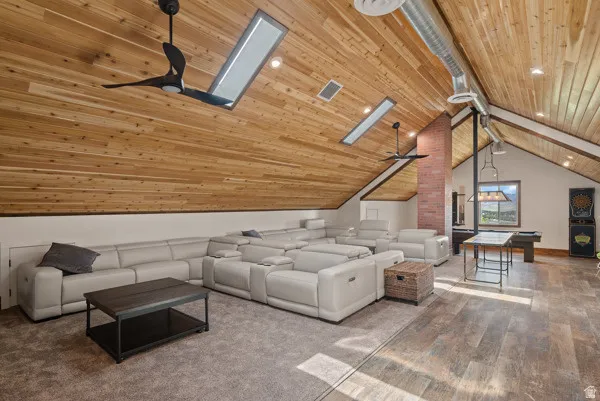 Living room featuring ceiling fan, wood-type flooring, a skylight, and a wooden ceiling with exposed beams