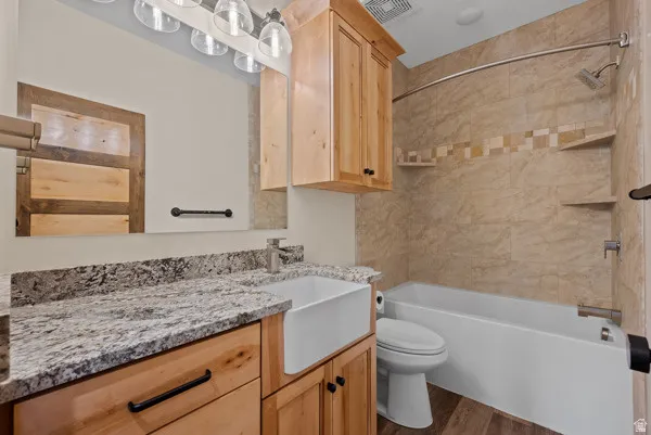 Bathroom with vanity, tub / shower combination, and dark wood-style flooring