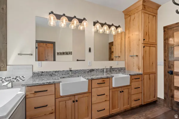 Bathroom featuring a garden tub, double vanity, and dark wood finished floors