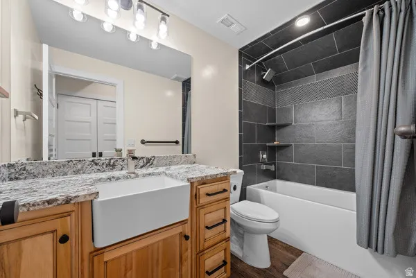 Bathroom with vanity, shower / tub combo, and dark wood-style flooring