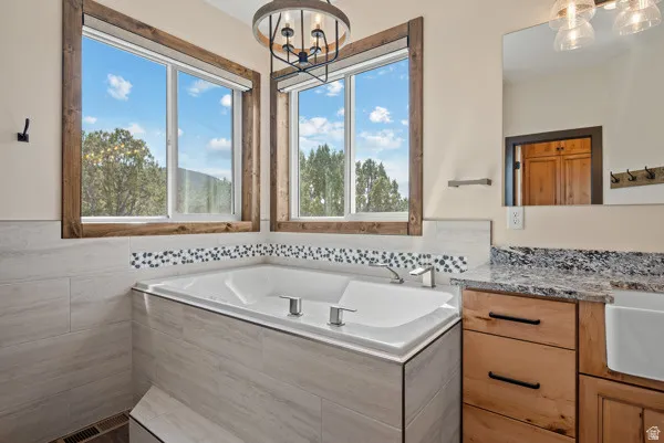Full bath featuring hanging lights, vanity, and a bath