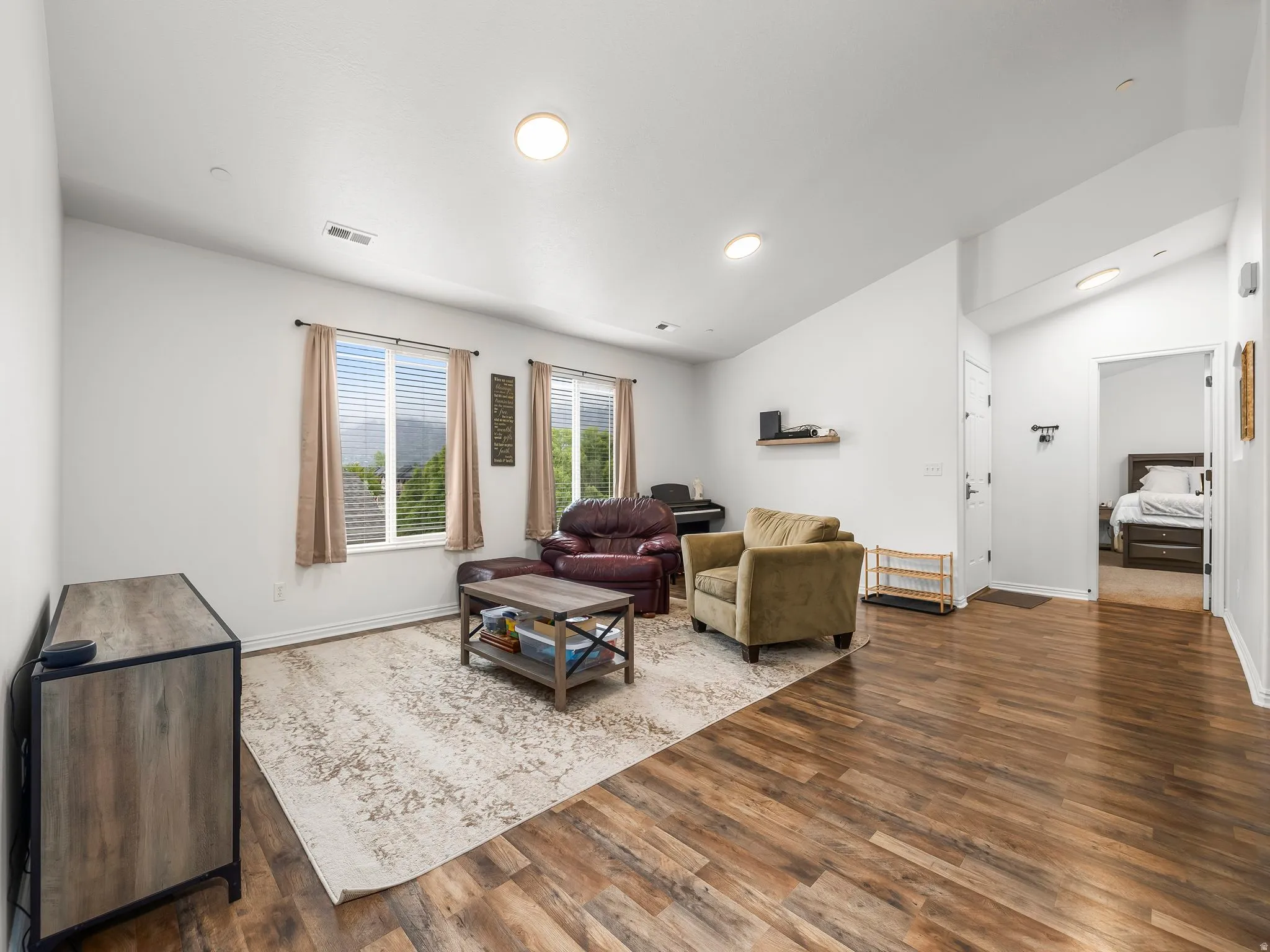 Living room with dark wood-style floors, vaulted ceiling, and recessed LED lighting