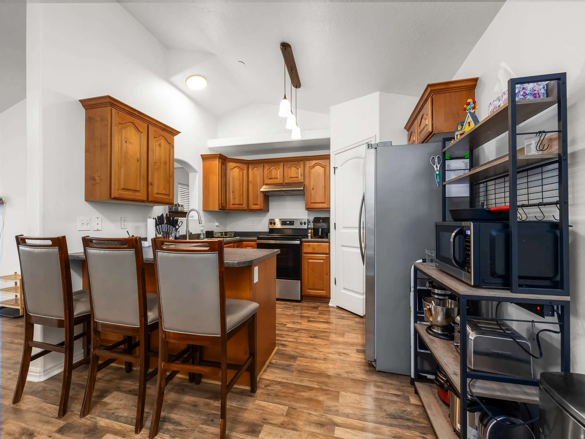 Kitchen featuring wood-finish flooring, recessed lighting, vaulted ceiling, wood cabinetry, and a kitchen island with seating