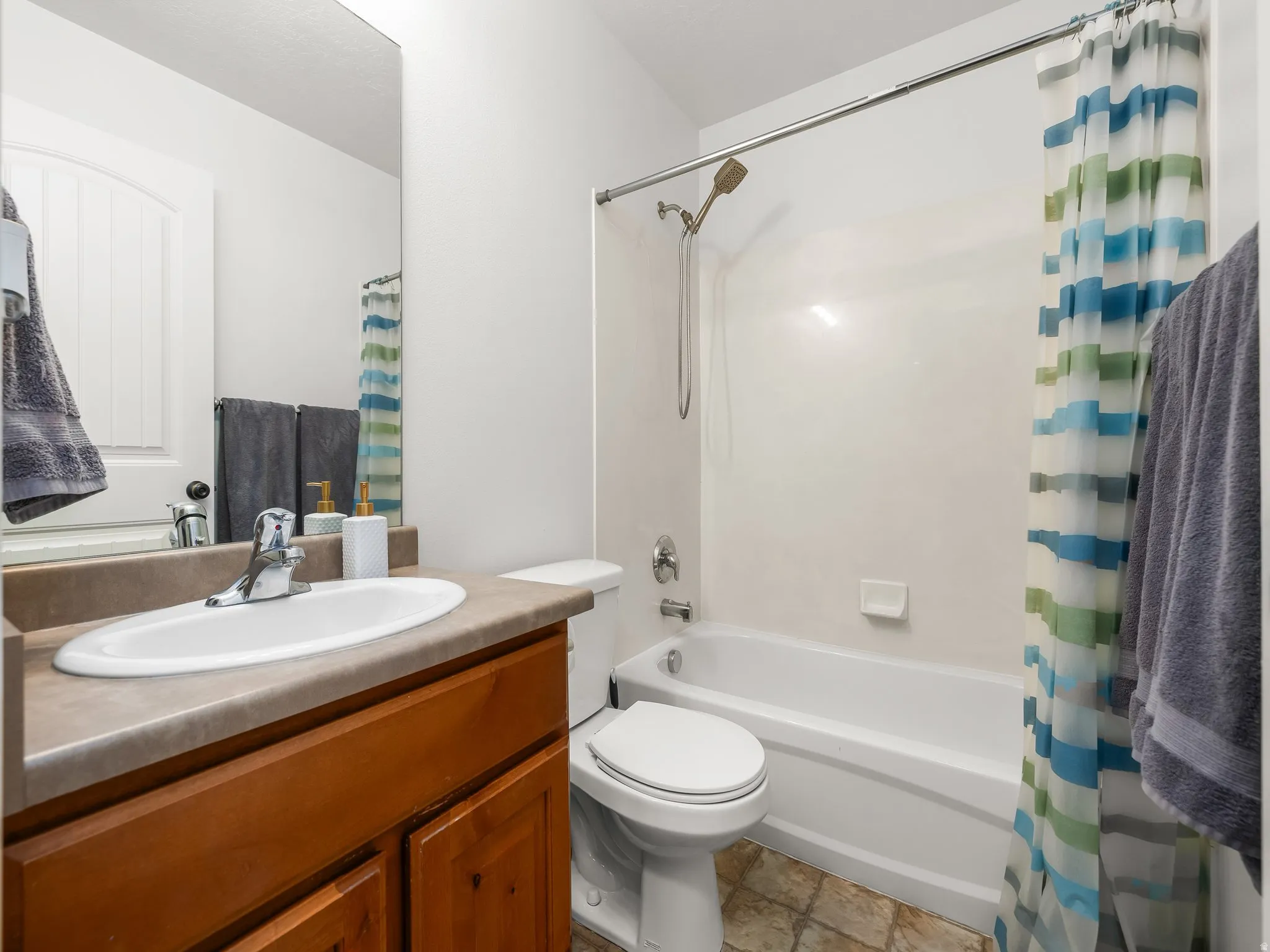 Bathroom featuring a wood-finish vanity with an integrated sink and a neutral-toned countertop