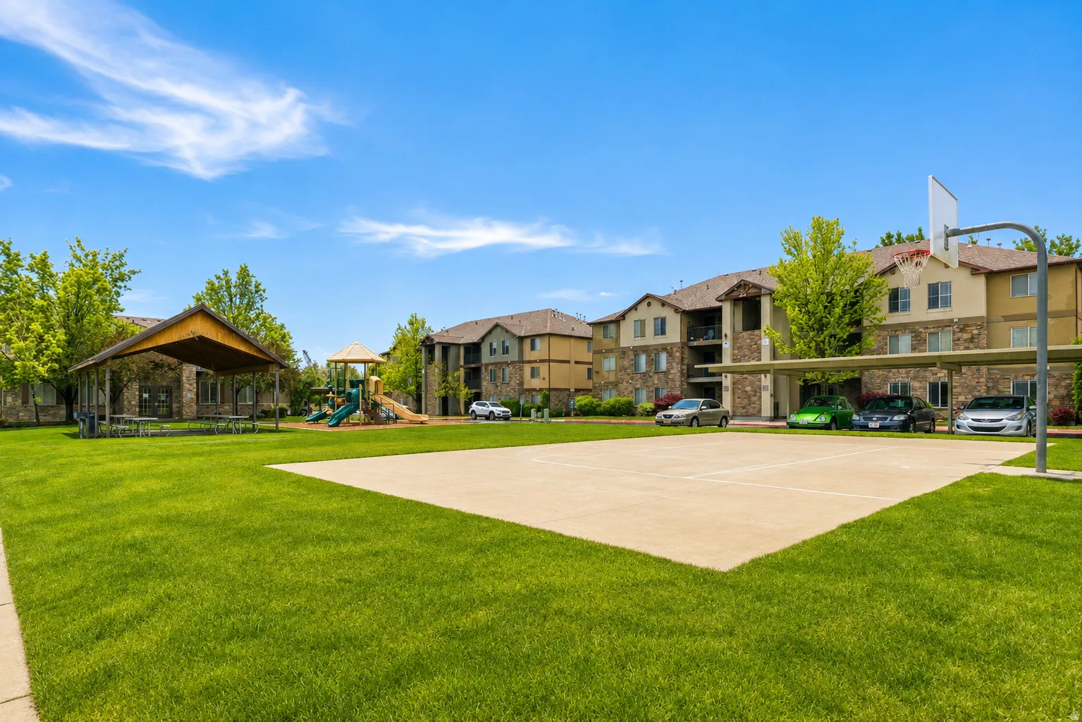 Expansive green lawn with a full-size basketball court, covered picnic area, and a dedicated play structure