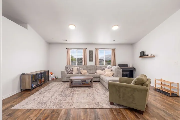 Spacious living area featuring wood-finish flooring, recessed lighting, and multiple windows