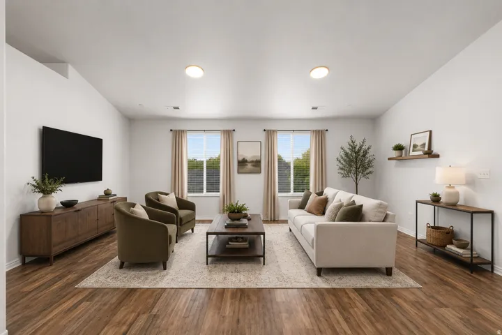 Bright, open living area showcasing hardwood flooring, recessed ceiling lighting, and multiple glass doors with transom windows framing natural light