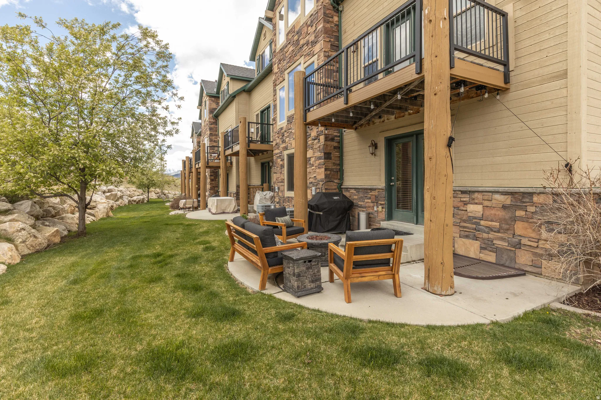 View of green lawn featuring a patio, an outdoor fire pit, and a balcony
