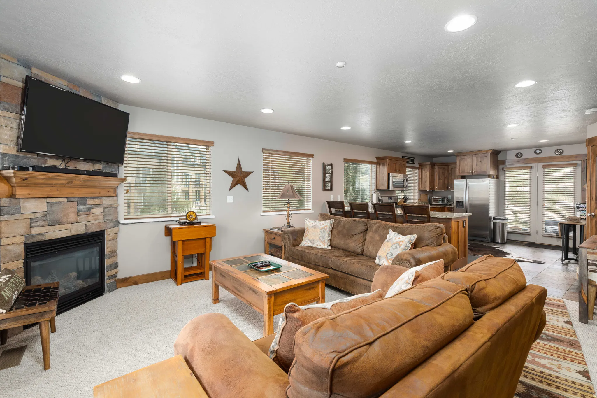 Living room with plenty of natural light, a stone fireplace, recessed lighting, and light carpet