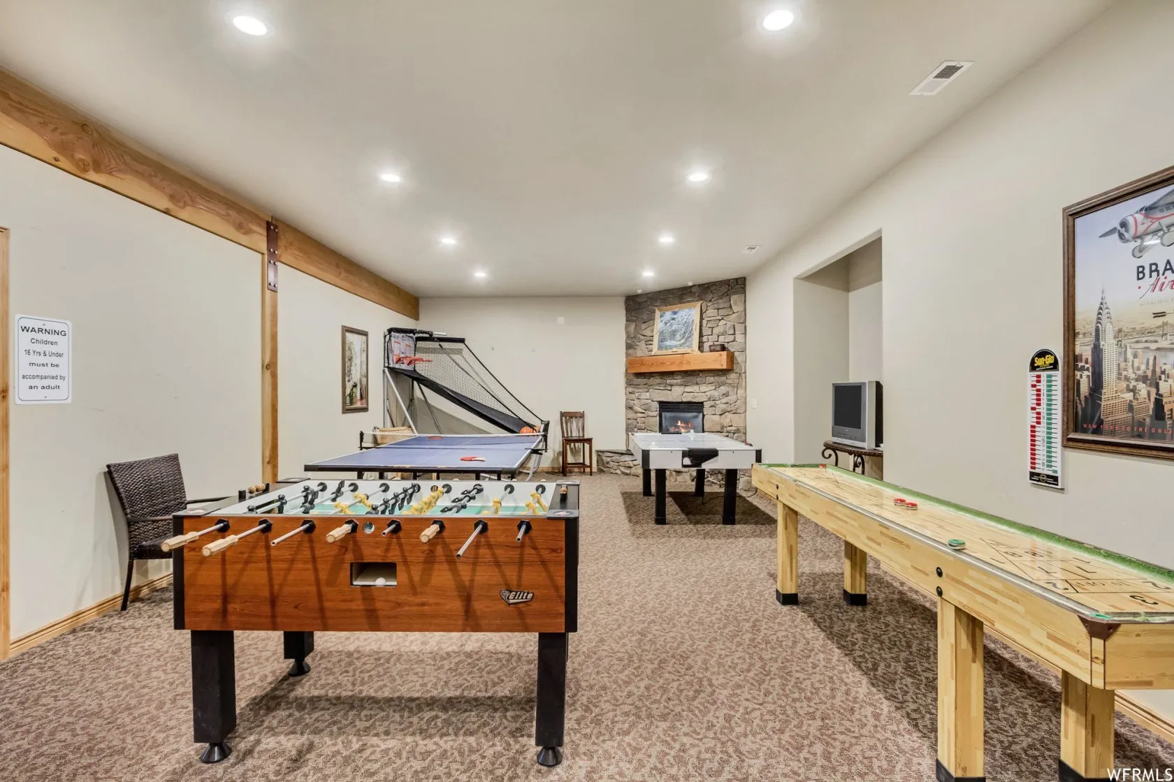 Recreation room with light colored carpet, recessed lighting, and a fireplace