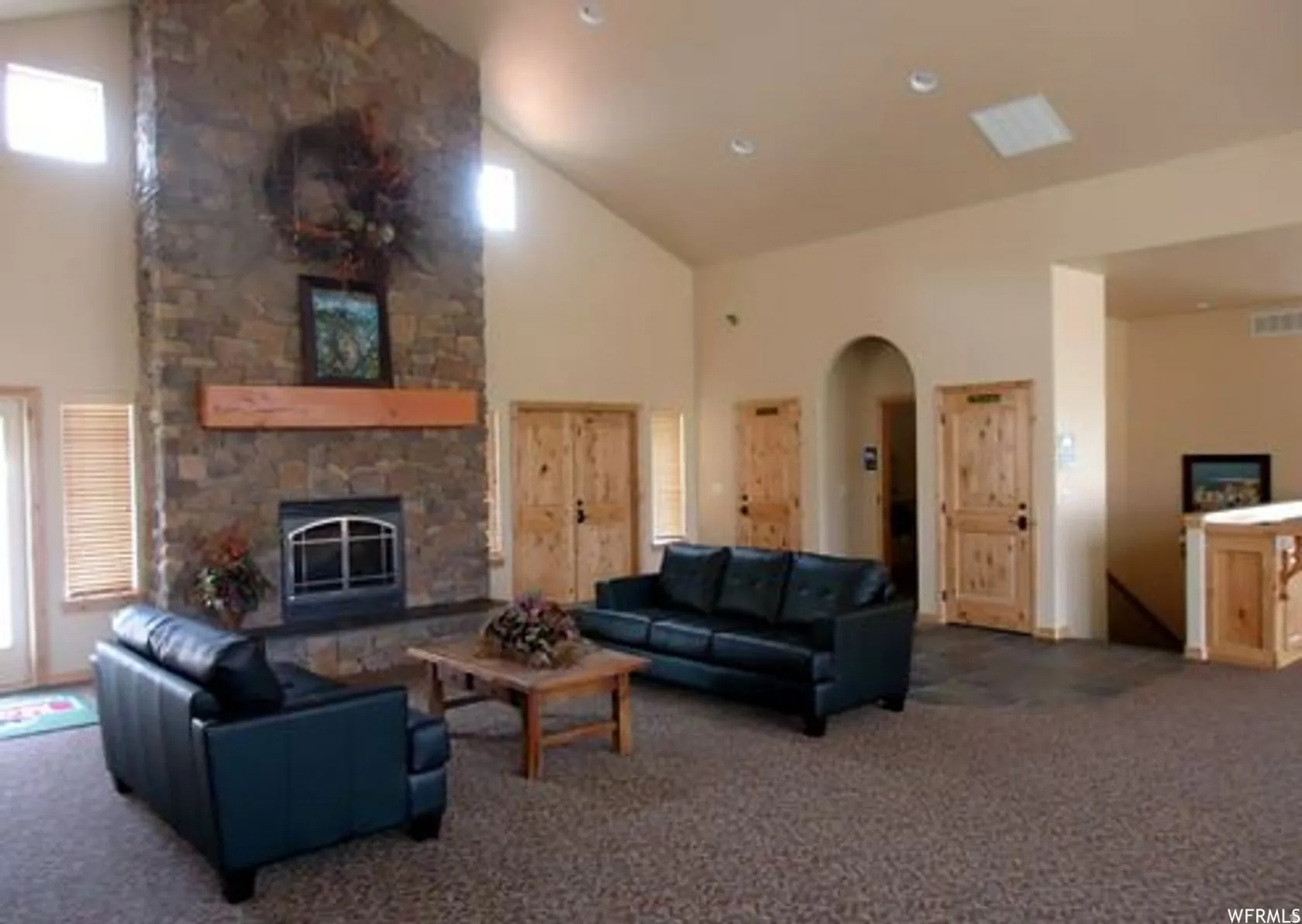 Carpeted living room featuring a fireplace, arched walkways, and lofted ceiling