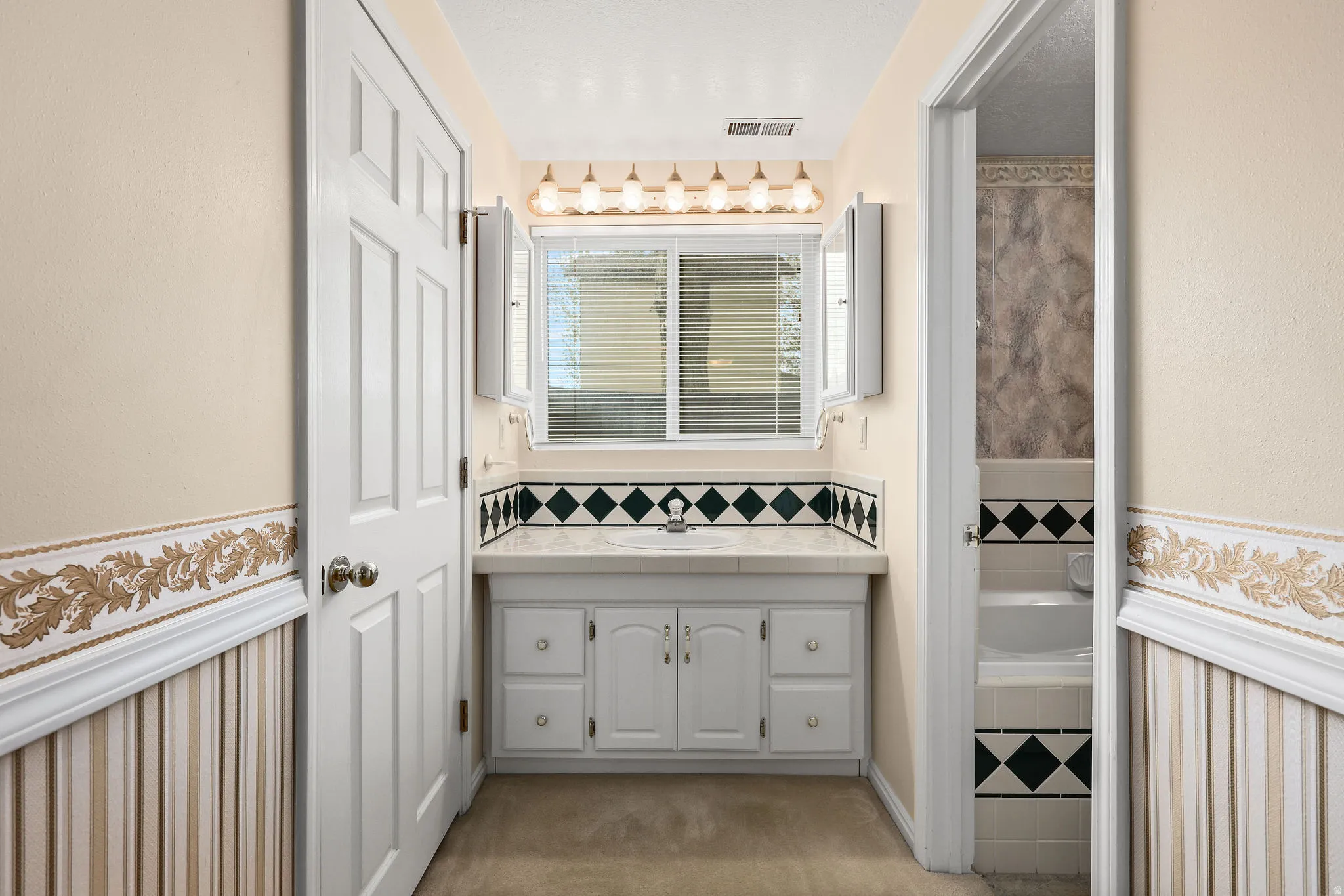 Bathroom with vanity, a bath, and a textured wall