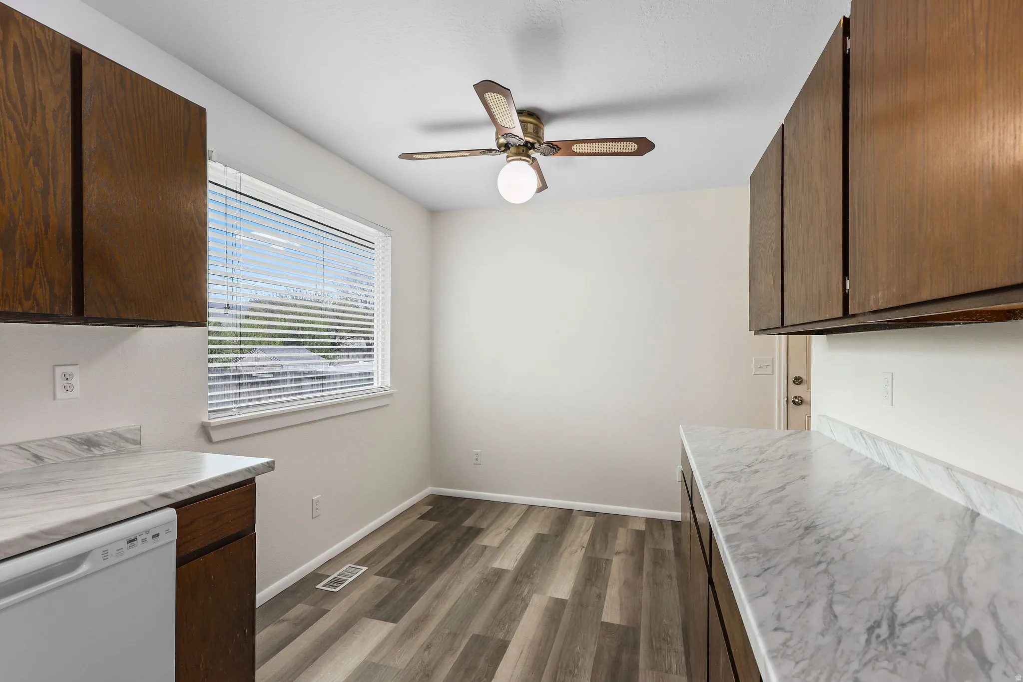 Kitchen with light countertops, white dishwasher, dark wood-type flooring, a ceiling fan, and dark wood finish cabinets