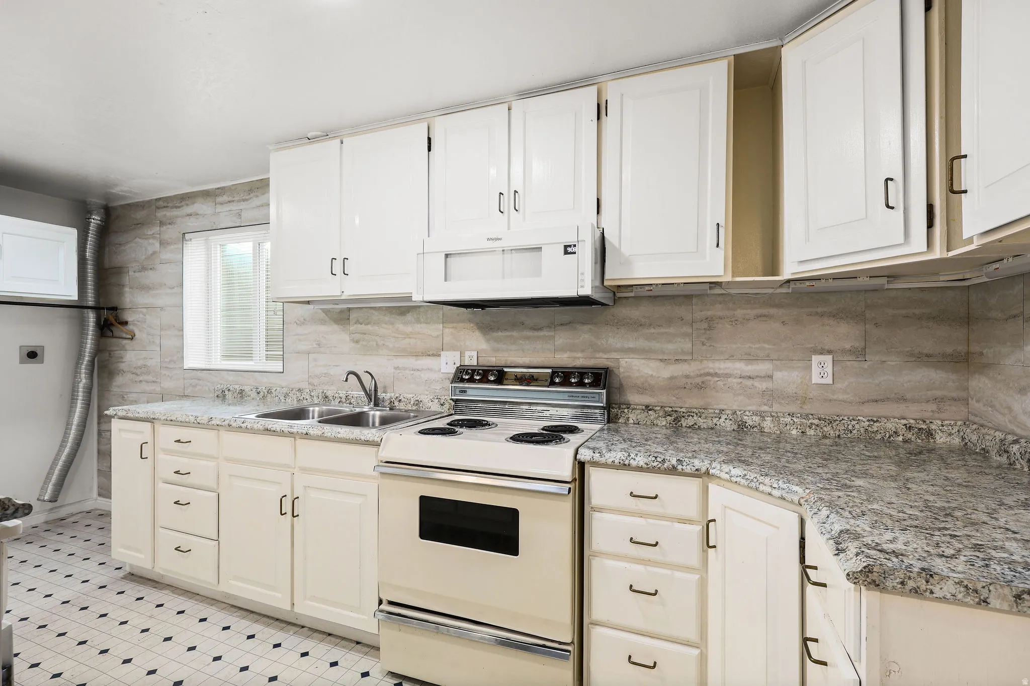 Kitchen featuring white appliances, backsplash, and white cabinetry