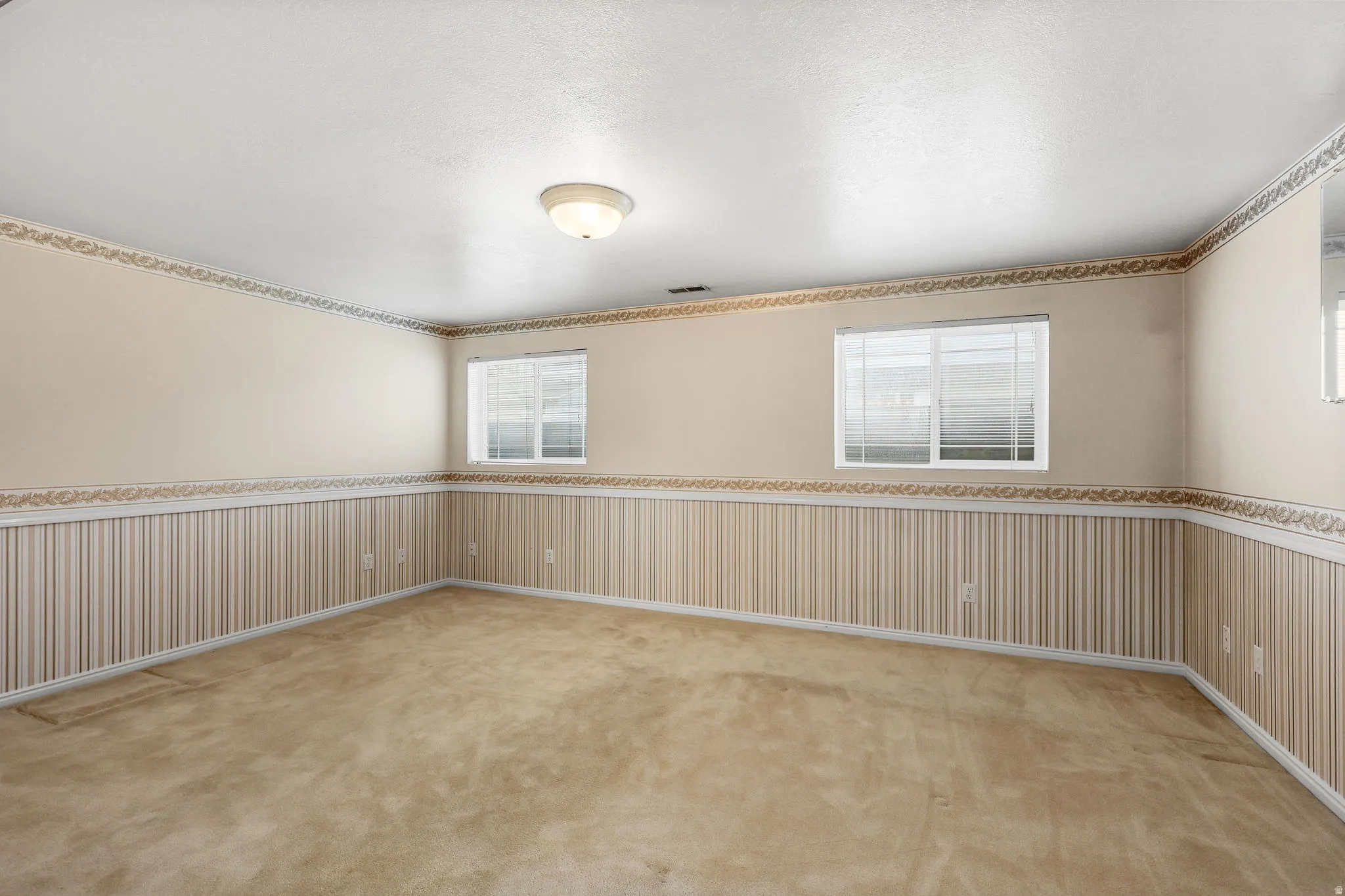 Empty room featuring wainscoting and light carpet