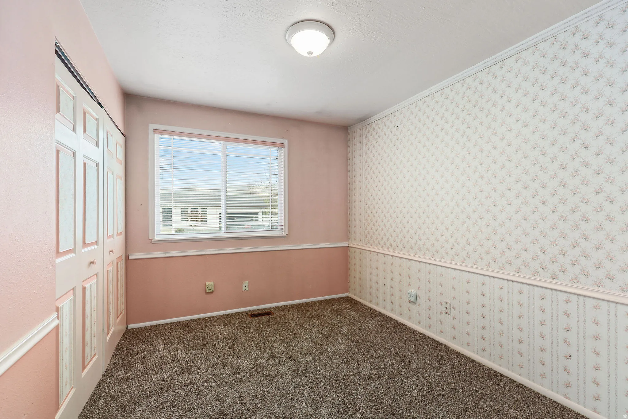 Unfurnished bedroom with wallpapered walls, a closet, dark carpet, and ornamental molding