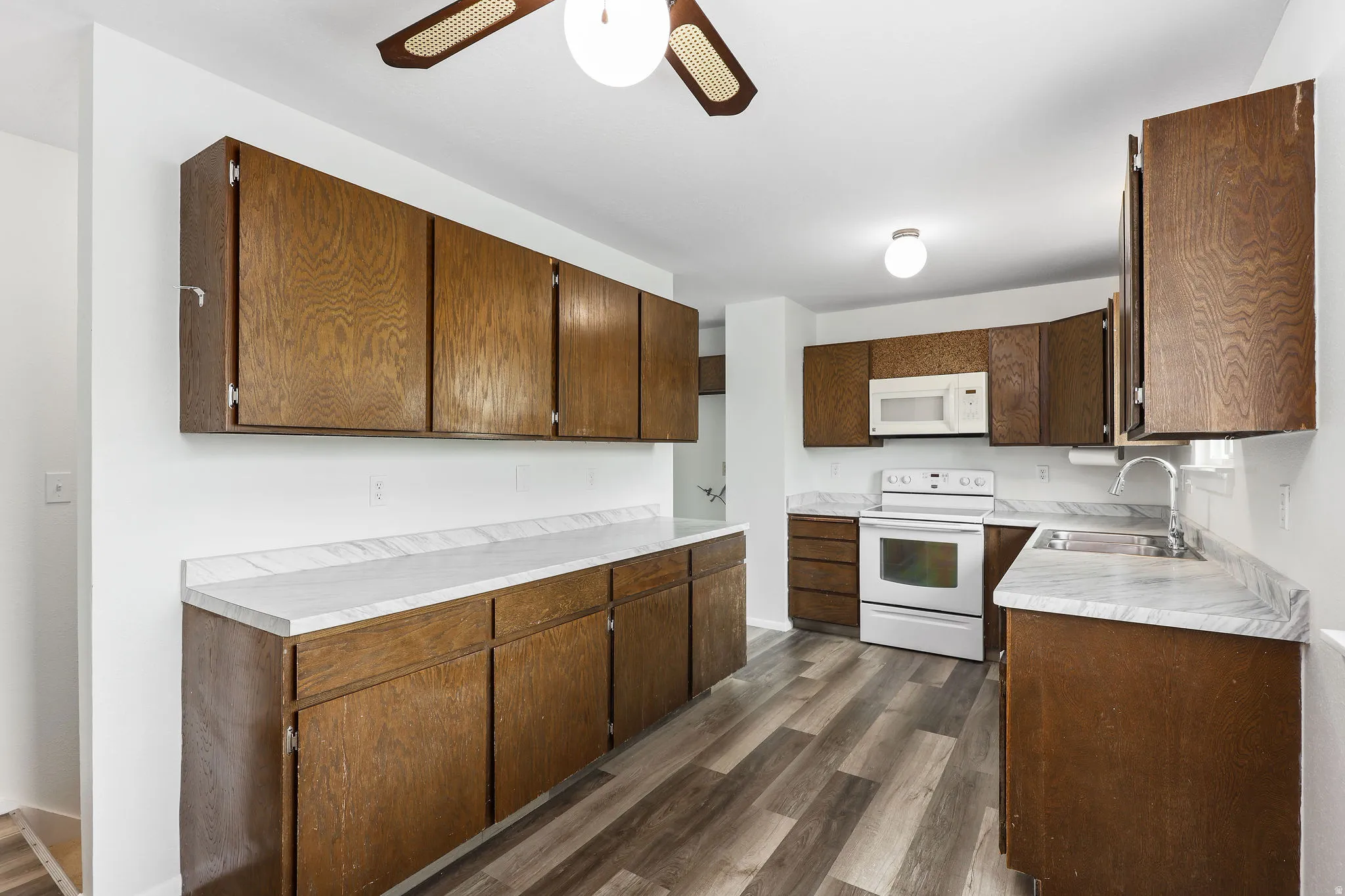 Kitchen featuring light countertops, dark wood-style flooring, and white appliances