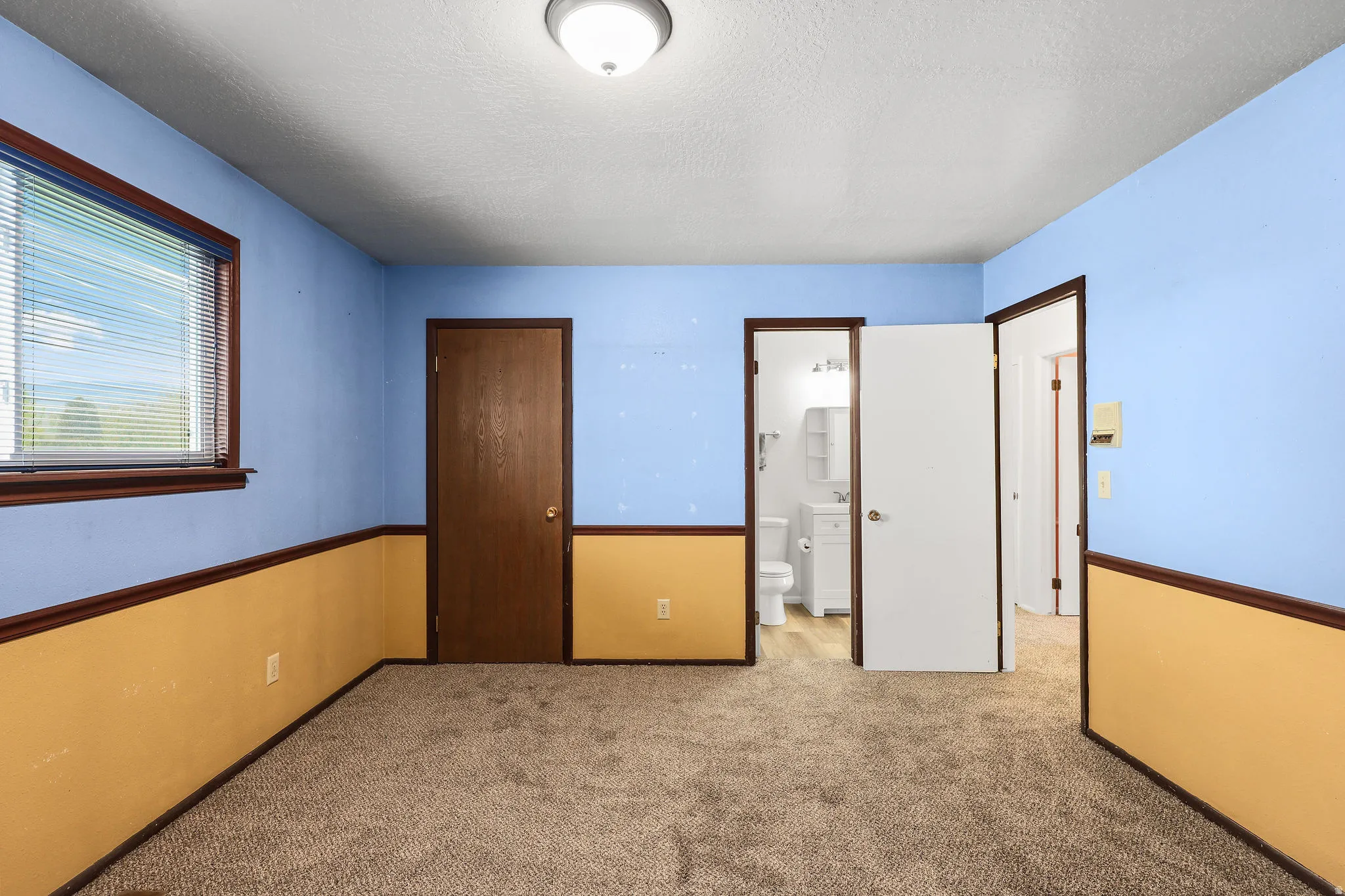 Unfurnished bedroom featuring light carpet, a textured ceiling, and ensuite bathroom