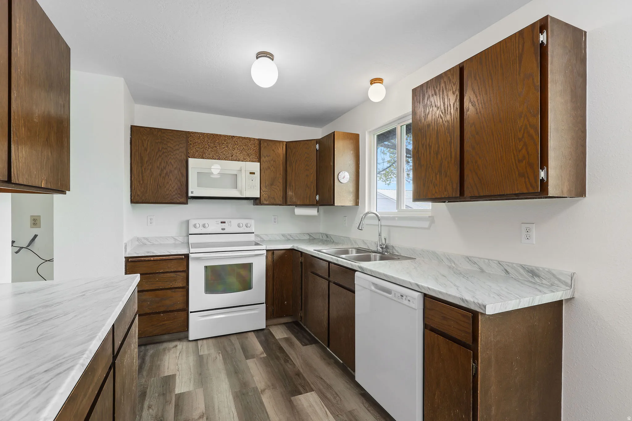 Kitchen featuring white appliances, light countertops, dark wood-style floors, and dark wood finish cabinetry