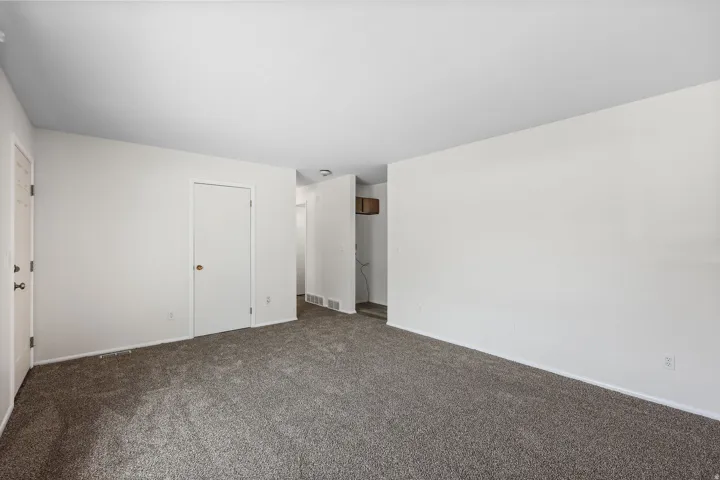Unfurnished bedroom with dark colored carpet and baseboards