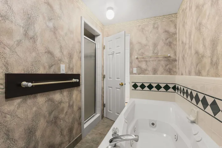 Full bath featuring a stall shower and a whirlpool tub