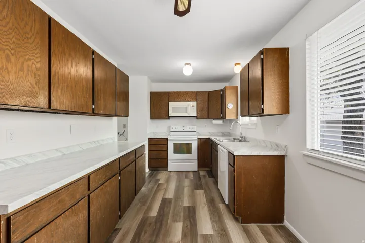 Kitchen featuring light countertops, white appliances, dark wood-style floors, and a ceiling fan