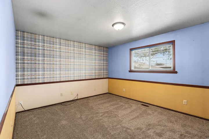 Empty room featuring wallpapered walls, carpet floors, and a textured ceiling