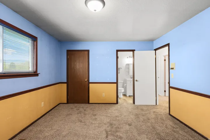 Unfurnished bedroom featuring light carpet, a textured ceiling, and ensuite bathroom