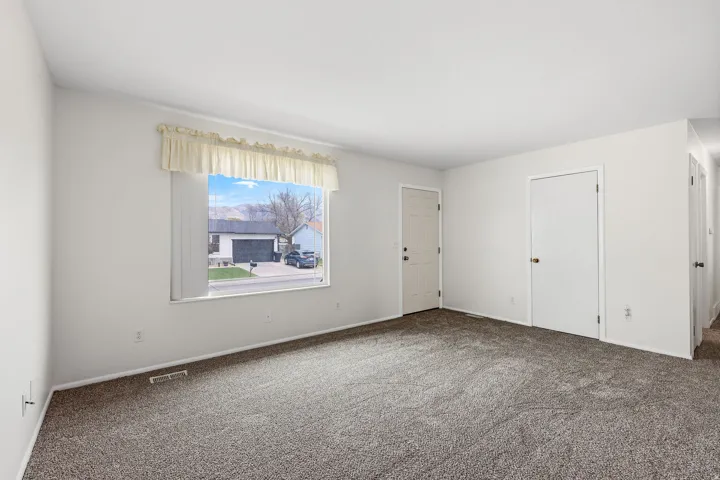 Carpeted spare room featuring baseboards