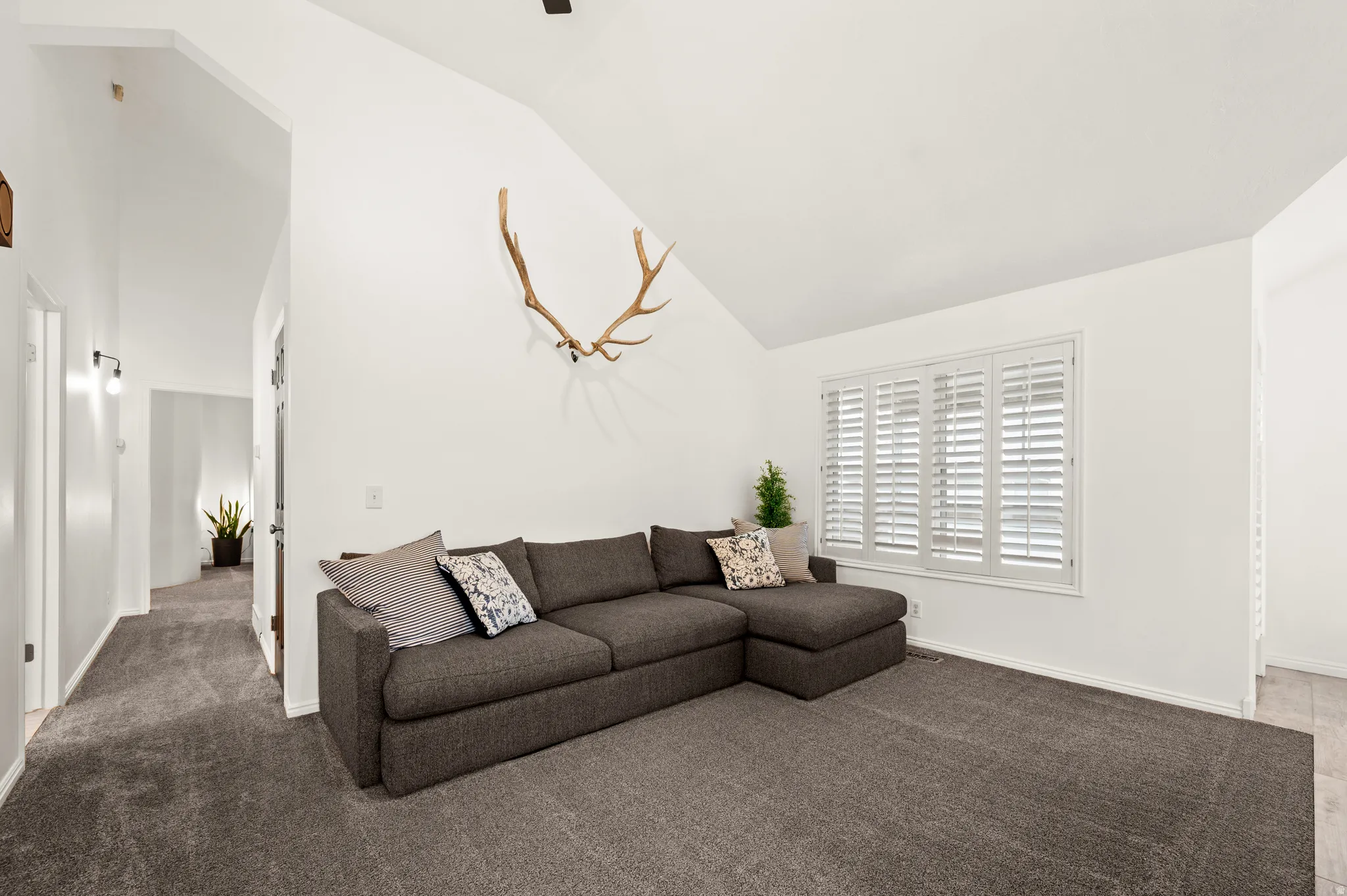 Carpeted living room featuring lofted ceiling and baseboards