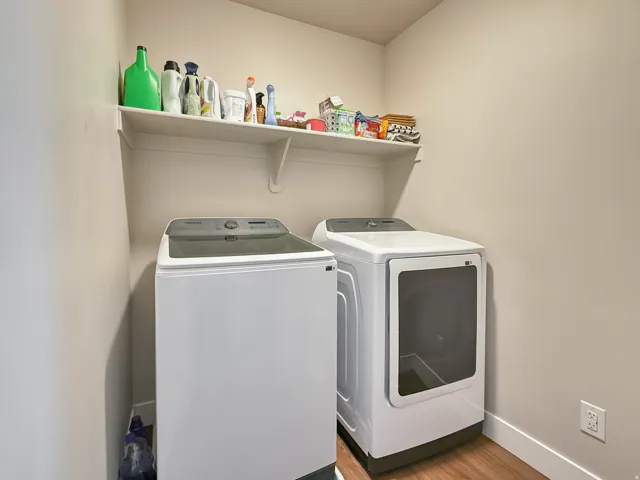 Laundry room with independent washer and dryer and light wood-type flooring