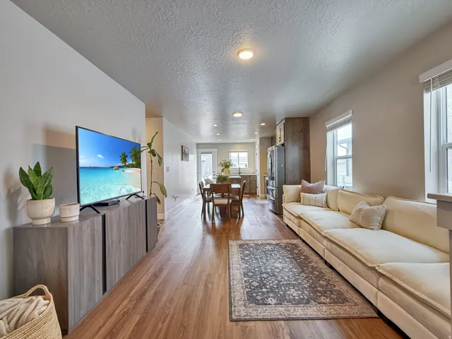 Living room featuring a textured ceiling, light wood-style floors, and healthy amount of natural light