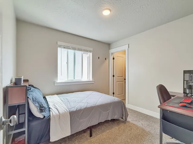 Bedroom featuring carpet, a desk, and a textured ceiling
